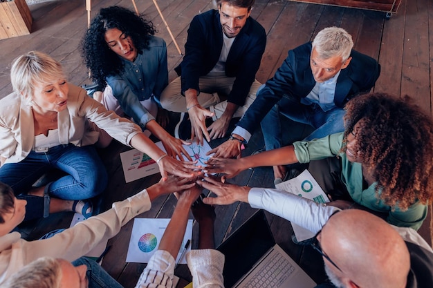 Group of people working in team sitting on circle on floor with positive vibes