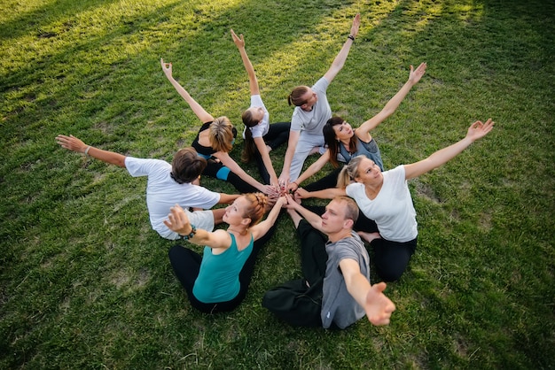 A group of people do yoga in a circle in the open air during sunset