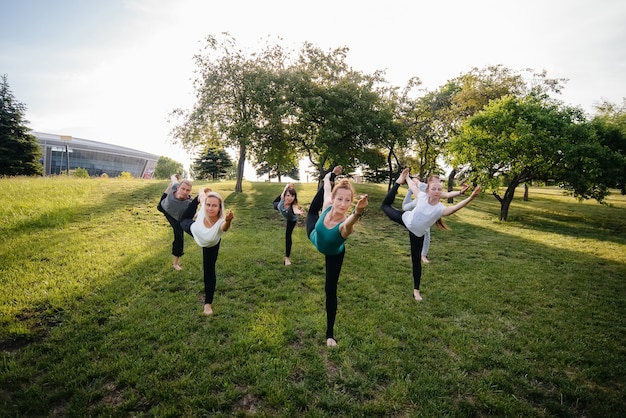 A group of people do yoga in the Park at sunset