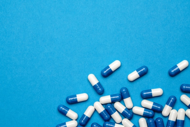 Group of pills or capsules on blue background.