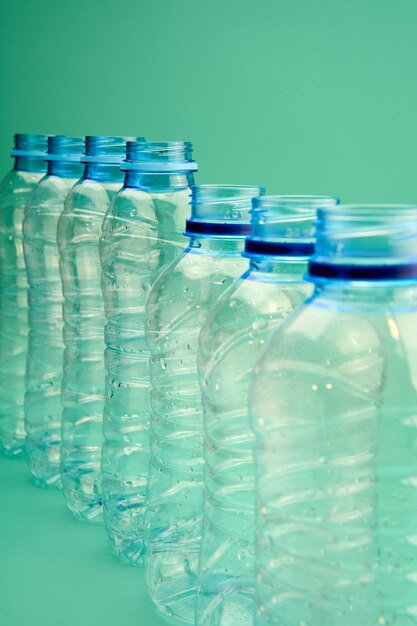 Photo group of plastic bottles for recycling placed in a row on a green background