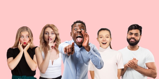 Group portrait of emotional people on coral pink studio wall