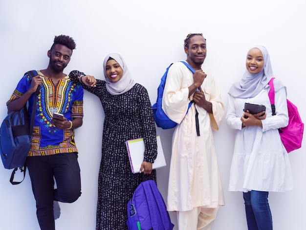 group portrait  of happy african students standing together against white background girls wearing traidiional sudan muslim hijab fashion