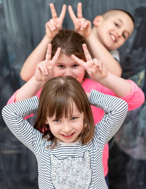 group portrait of happy childrens standing one behind the other while having fun in front of black chalkboard