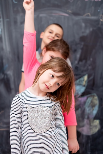 group portrait of happy childrens standing one behind the other while having fun in front of black chalkboard