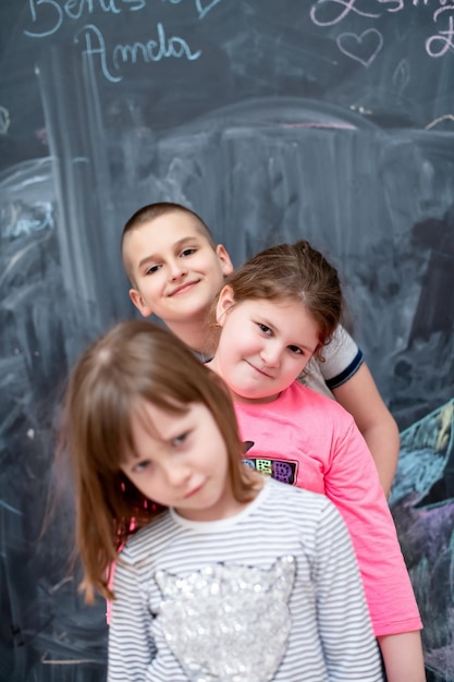 group portrait of happy childrens standing one behind the other while having fun in front of black chalkboard