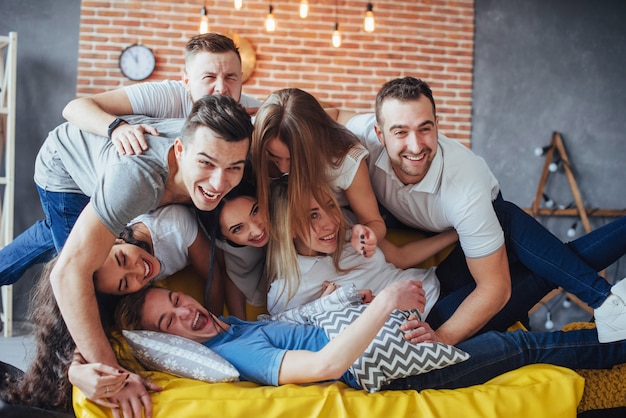 Group portrait of multi-ethnic boys and girls with colorful fashionable clothes holding friend posing on a brick wall, Urban style people having fun, s about youth togetherness lifestyle