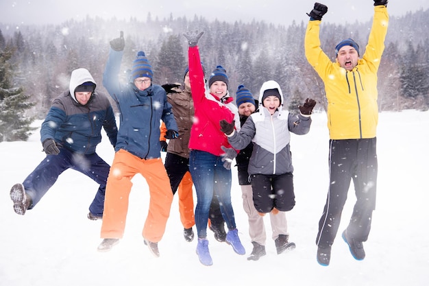 group portrait of young happy business people enjoying snowy winter day with snowflakes around them during a team building in the mountain forest