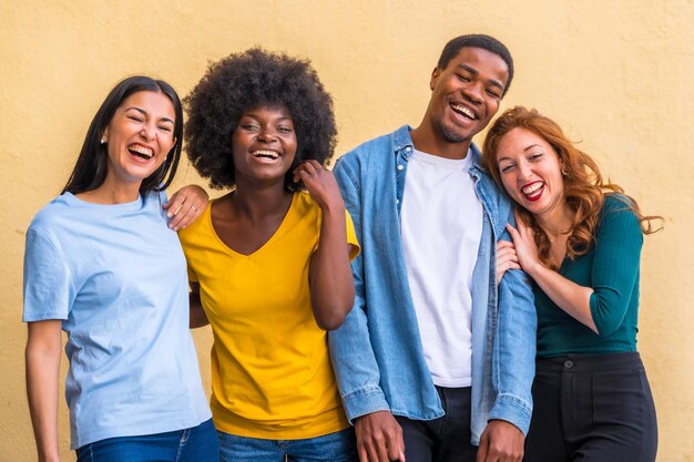 Group portrait of young multi ethnic student friends against yellow wall international youth community people concept