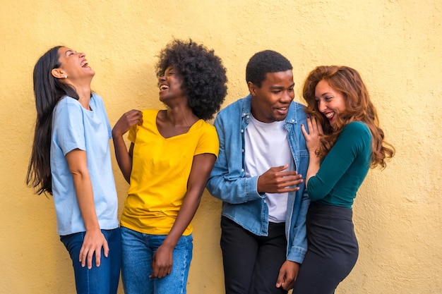 Group portrait of young multiethnic friends against yellow wall international youth community