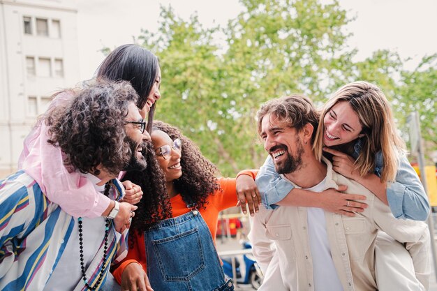 Foto un gruppo di persone positive, gioiose e multirazziali che si cavalcano sulle spalle mentre si divertono all'aperto