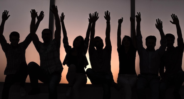 Photo group of positive young people sitting on a windowsill