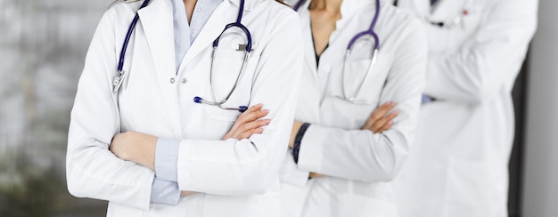 Group of professional doctors is standing as a team with arms crossed in clinic. Medicine concept during Coronavirus pandemic.