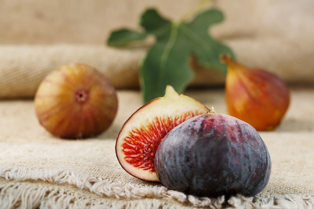 Group of purple and green figs on a farm wooden table with burlap cloth