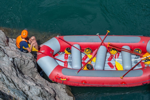 Foto il gruppo di rafting e canottaggio sulla guida del fiume di montagna è seduto sulla riva in attesa del gruppo barca vuota