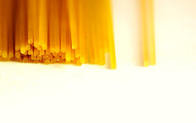 Photo a group of raw spaghetti stacked on a white surface dried durum wheat pasta ready to be cooked