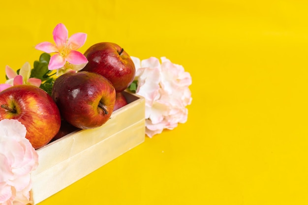 Group of red apples in wooden box on yellow background