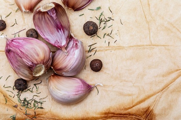 Group of red garlic cloves, black pepper balls and other spices. On a beautiful rustic vanilla colored background. Space to insert your text (Copy text)