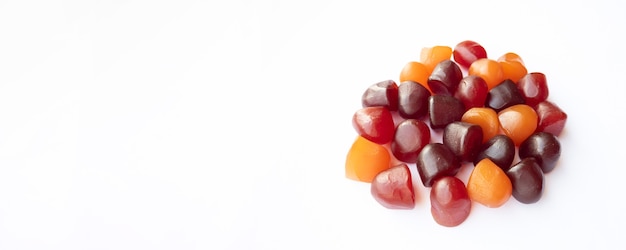 Gruppo di caramelle gommose multivitaminiche rosso arancio e viola isolato su sfondo bianco stile di vita sano