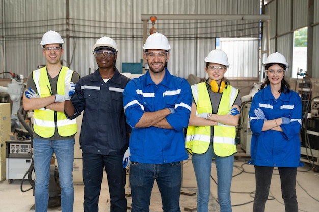 Group of robotic engineers standing and arms crossed at factory workshop