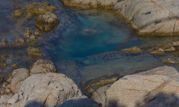 A group of rocks surround some emerald waters 