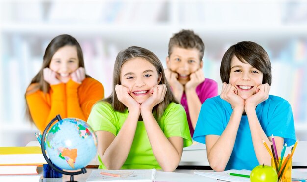 Photo group of school kids in classroom with hands raised