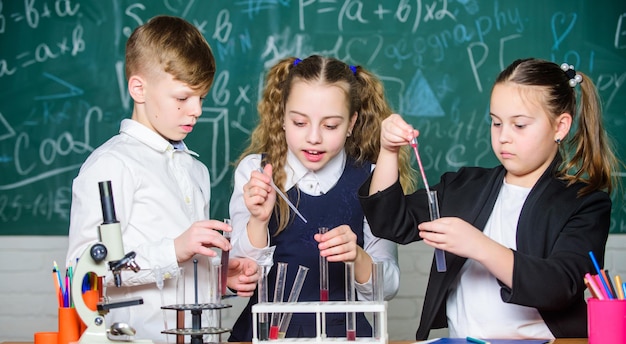Group school pupils study chemical liquids girls and boy\
student conduct school experiment with liquids school chemistry\
lesson test tubes with substances formal education school\
laboratory