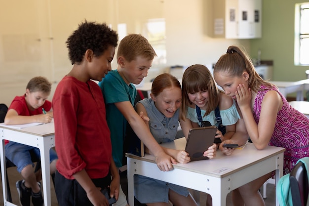 Foto gruppo di scolari attorno a una scrivania utilizzando un tablet pc
