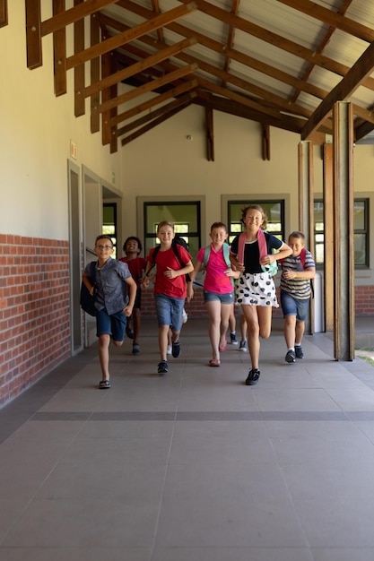 Группа школьников, бегущих по открытому коридору в начальной школе