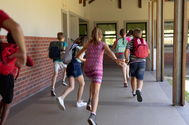 Photo group of schoolchildren running in an outdoor corridor at elementary school