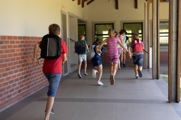 Foto gruppo di scolari che corrono in un corridoio all'aperto della scuola elementare