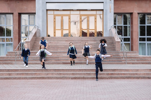 制服を着た小学生のグループが学校の外の階段を駆け下りています。