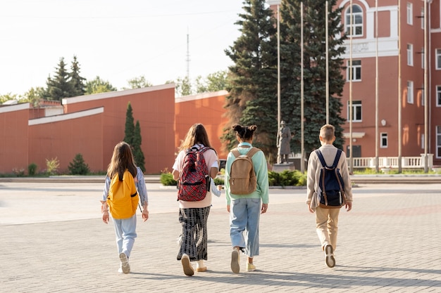 Group of schoolkids with backpacks going to school in the morning