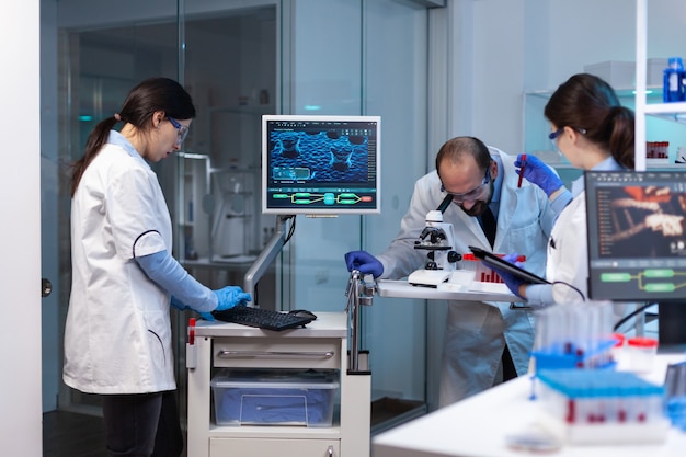 Group of scientists doing research and experiments at medical lab against disease with special equipment