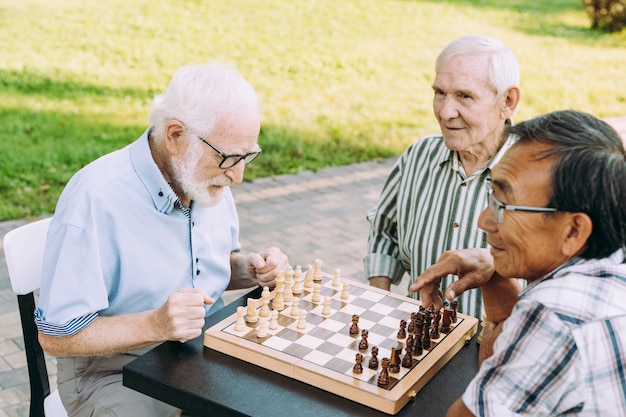 Group of senior friends playing chess game at the park. Lifestyle concepts about seniority and third age