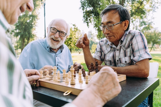 Группа старших друзей, играющих в шахматы в парке. Концепции образа жизни о старшинстве и третьем возрасте