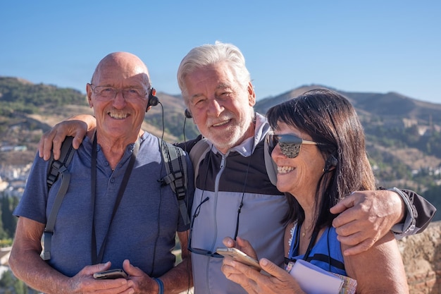 Group of senior friends visiting Granada listening to informations via audio guide enjoying vacation