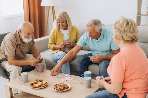 Group of senior people laughing while relaxing at home and playing cards