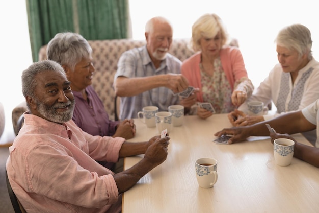 Photo group of senior people playing cards in living room