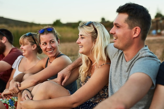 Group sitting and people with nature relax and calm with peace summer holiday and vacation Happy friends outdoor and men with women funny and weekend break with view travel and getaway trip