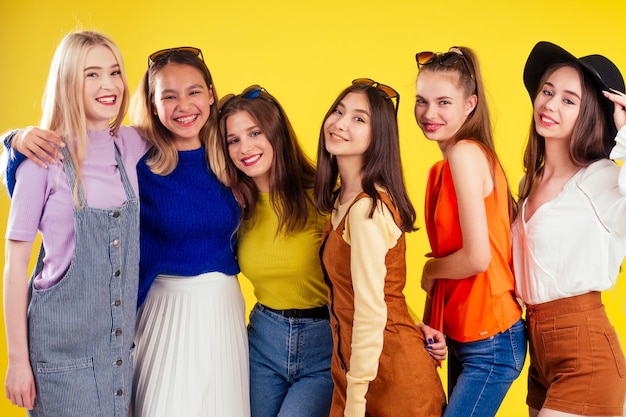 Group of six laughing girls having party summer style yellow background studio