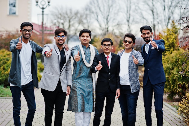 Group of six south asian indian mans in traditional casual and business wear standing and shows thumb up