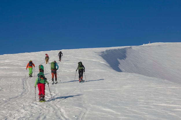 Group of skiers and snowboarders climbing up teamwork