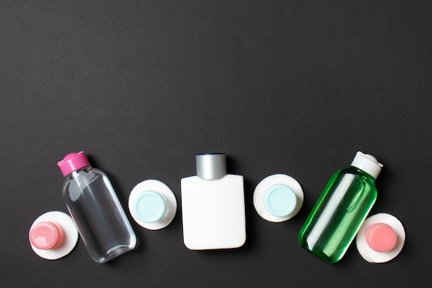 Group of small bottles for travelling on colored background. Copy space for your ideas. Flat lay composition of cosmetic products. Top view of cream containers with cotton pads.