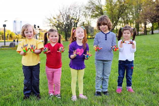 Un gruppo di bambini piccoli con le mani sporche in vernice di colore gioca nel parco.