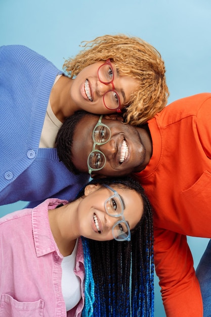 Group of smiling African American friends wearing colorful glasses isolated on blue background