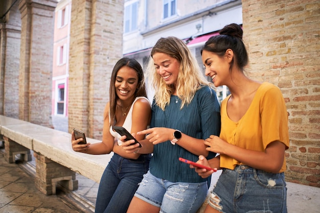 Group of smiling female friends watching social media at smartphone