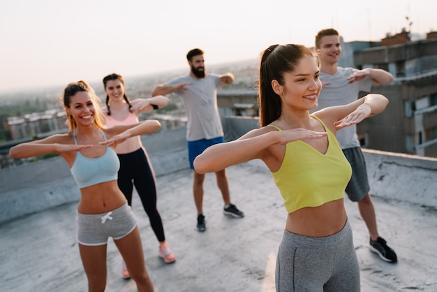 Group of smiling fit happy people doing power fitness exercise outdoor