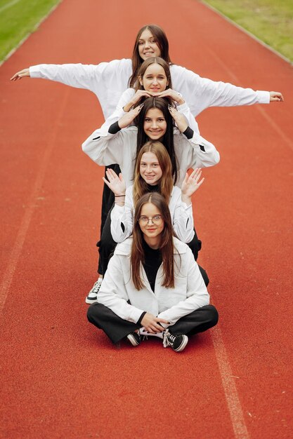 A group of smiling and happy teenage friends dressed in casual clothes spend time together pose and have fun on the grounds of an educational institution on an autumn day