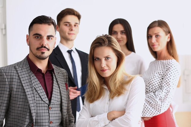 Group of smiling people stand in office looking in camera